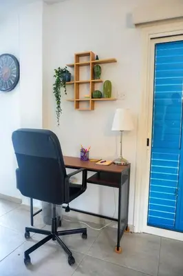 an office with a desk and a chair and a lamp at Kapparis Avenue Beach Apartment in Paralimni