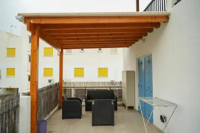 a patio with a wooden pergola next to a building at Kapparis Avenue Beach Apartment in Paralimni
