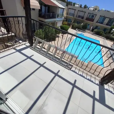 a balcony with a fence and a swimming pool at Cydonia Gardens Maisonette with shared pool in Limassol