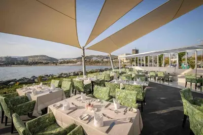 a restaurant with tables and chairs with a view of the water at Cydonia Gardens Maisonette with shared pool in Limassol
