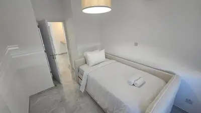a small white bedroom with a bed and a mirror at Sea Breeze 3 Bed Frontline Flat in Limassol