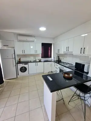 a kitchen with white cabinets and a black counter top at At Patara Site, the heart of Kyrenia in Aglantzia