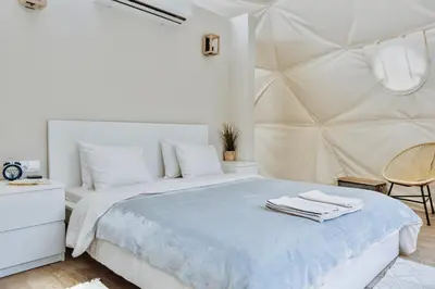 a white bedroom with a bed and a chair at Geometry Park in Ayios Theodhoros
