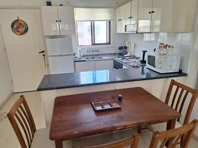 a kitchen with a wooden table and a counter top at Easy 2 bedroom apartment, Makenzi beach in Larnaka