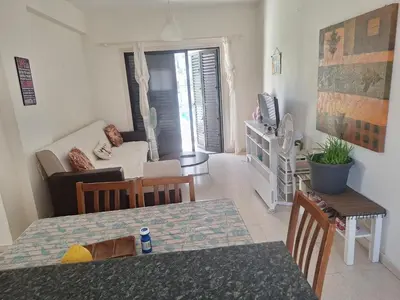 a living room with a table and a living room with a couch at Easy 2 bedroom apartment, Makenzi beach in Larnaka