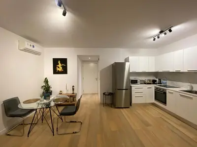 a kitchen with white cabinets and a table and a refrigerator at Stylish Apt near UNIC Medical School & EUC in Engomi