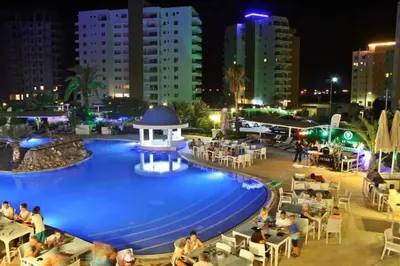 a swimming pool with people sitting around it at night at Marcellus in Larnaka