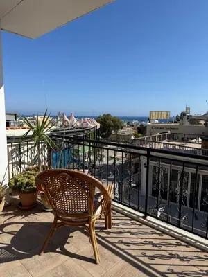 a wooden chair sitting on a balcony with a view at One Love One World Ayia Napa Square Hostel in Ayia Napa