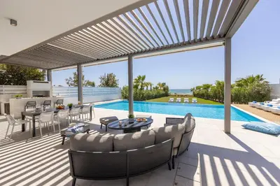 a patio with a table and chairs and a pool at Villa JoJo Seafront in Ayia Napa