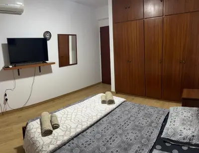 a bedroom with a bed with slippers and a tv at Tiffany 11 Finikoudes in Larnaka