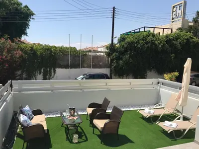 a patio with chairs and tables on the grass at STAY Paradise Sands Studio in Ayia Napa