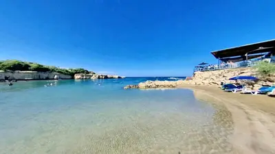 a beach with a group of chairs and the water at Mythical Sands Resort and Spa in Paralimni
