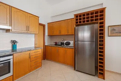 a kitchen with wooden cabinets and a stainless steel refrigerator at Villa Thea, Luxury Cliff Sea View in Pissouri