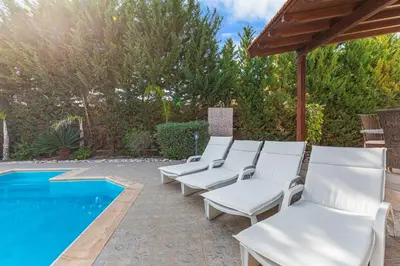 a row of white chairs next to a swimming pool at Villa Thea, Luxury Cliff Sea View in Pissouri