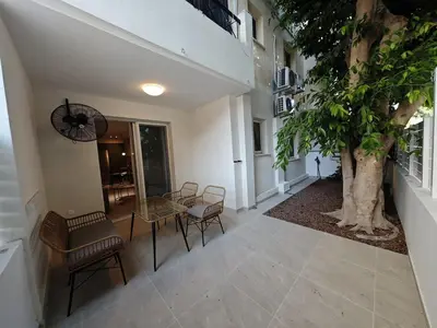 a hallway with chairs and a table and a tree at Ficus Suite 001 in Voroklini
