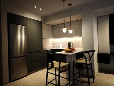 a kitchen with a table with chairs and a refrigerator at Ficus Suite 001 in Voroklini