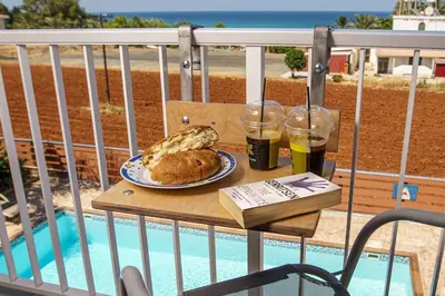a table with a plate of food and drinks on a balcony at STAY Villa Kangaroo in Protaras