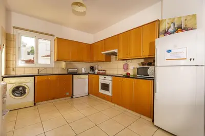 a kitchen with wooden cabinets and a white refrigerator at STAY Villa Kangaroo in Protaras
