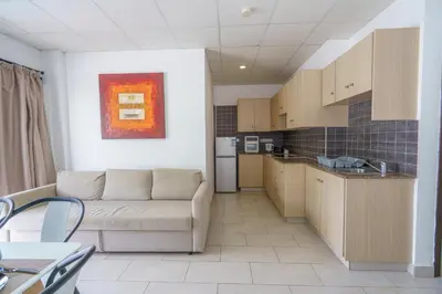 a living room with a couch and a kitchen at Pernera One Suites in Pernera Protaras in Paralimni