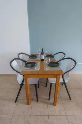 a wooden table with four chairs and a bottle of wine at Pernera One Suites in Pernera Protaras in Paralimni