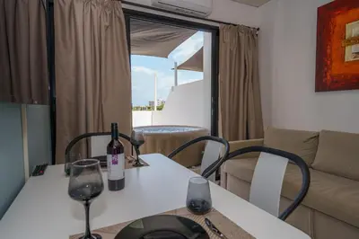 a table with two wine glasses and a couch at Pernera One Suites in Pernera Protaras in Paralimni