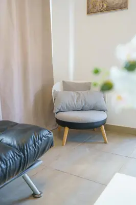a chair and a ottoman in a living room at Pernera One Suites in Pernera Protaras in Paralimni