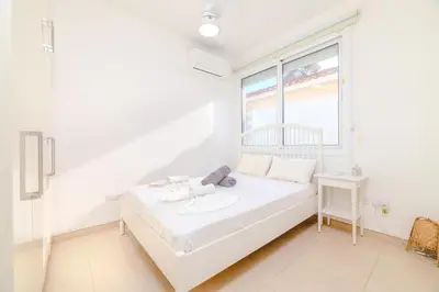 a white bedroom with a bed and a window at Ayia Thekla Beach House in Ayia Napa