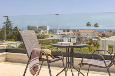 a table and chairs on a balcony with a view of a city at Villa Nissi 1 in Ayia Napa