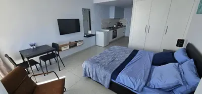 a bedroom with a bed and a table and a kitchen at Muhteşem Deniz Manzaralı Stüdyo in Iskele