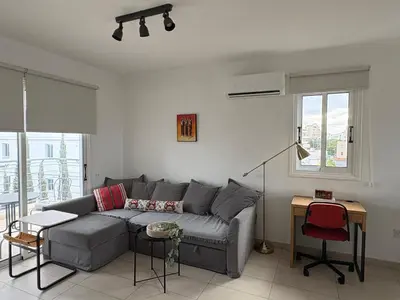 a living room with a gray couch and a table at Cozy Central Stay with City Views in Nicosia