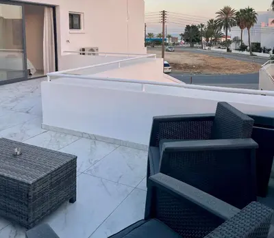 a patio with two chairs and a table on a building at FatCow Beach Apartment Ultra in Larnaka