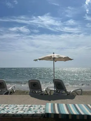 two chairs and an umbrella on the beach at FatCow Beach Apartment Ultra in Larnaka