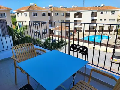 a balcony with a table and chairs and a swimming pool at Anemone - walk to the beach in Paralimni