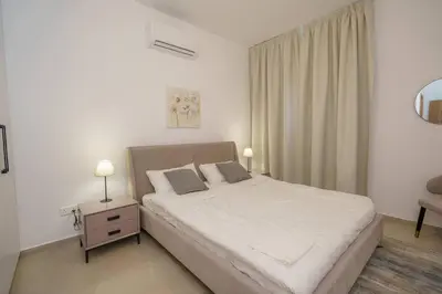 a bedroom with a bed and a table with two lamps at Kalamon Luxury Suite 105 w Pool & Gym in Livadhia