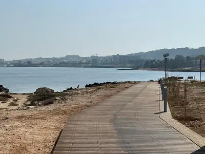 a boardwalk on a beach next to a body of water at Iliada Beach Hotel in Protaras