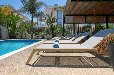 a row of benches next to a swimming pool at Villa Evergreen - 3bed Bungalow large pool in Protaras