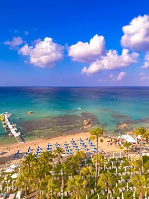 a beach with umbrellas and chairs and the ocean at Silver Sands Beach Hotel in Protaras