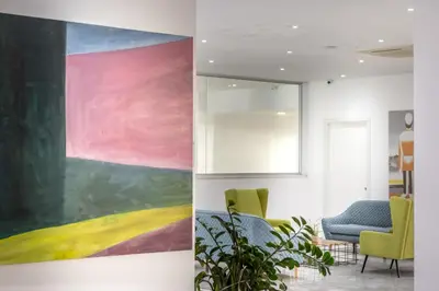 a large painting on the wall in a room with chairs at Papantonia Hotel in Protaras
