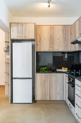 a white refrigerator in a kitchen with wooden cabinets at Aeolis Court Apartment by Ezoria Villas in Limassol