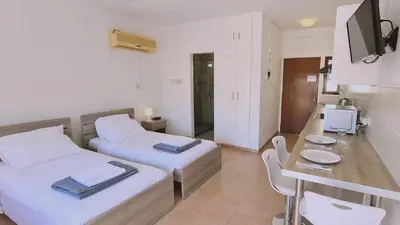 a room with two beds and a table and a kitchen at STAY Nissi Heaven Studio in Ayia Napa
