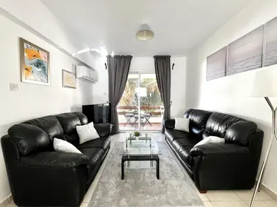 a living room with a black leather couch and a table at STAY Napa Dreams Apartment in Ayia Napa