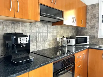 a kitchen with wooden cabinets and a black counter top at STAY Napa Dreams Apartment in Ayia Napa