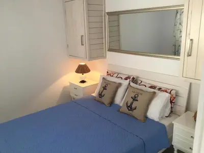 a bedroom with a blue bed and a mirror at Pissouri Beach Front Apartments in Pissouri