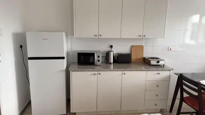 a kitchen with white cabinets and a white refrigerator at Sun Shine Studio With Balcony in Larnaka