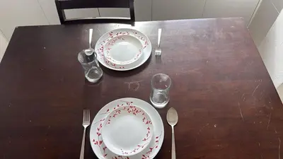 a wooden table with two plates and forks and glasses at Sun Shine Studio With Balcony in Larnaka