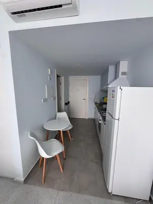 a kitchen with a white refrigerator and a table and chairs at A peaceful apartment with sea views in Aglantzia
