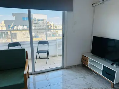 a living room with a flat screen tv and a chair at Central Rooms, 500m to Larnaca Marina in Larnaka