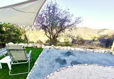a chair and an umbrella next to a swimming pool at Olive Grove Mountain Caravan in Limnatis