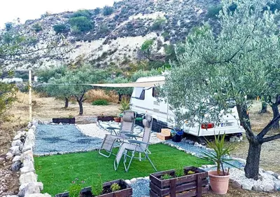 an rv parked in a yard with a table and chairs at Olive Grove Mountain Caravan in Limnatis