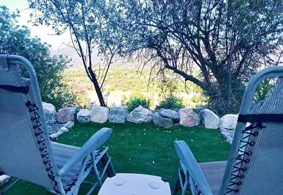 two chairs sitting on a patio with a yard with rocks at Olive Grove Mountain Caravan in Limnatis